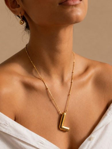 Découvrez le Collier Initiale L Élégance™. Une chaîne perlée dorée raffinée avec pendentif lettre L au design minimaliste et intemporel. Le cadeau parfait pour elle.