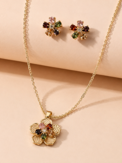 Découvrez la Parure Fleur Aurora™. Un ensemble collier et boucles d'oreilles dorés ornés de cristaux multicolores inspirés des fleurs en éclosion. Élégance et éclat garantis.