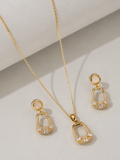 Découvrez la Parure Élégance Perle Royale™. Ensemble collier et boucles d'oreilles dorés ornés de cristaux étincelants et d'une pierre nacrée élégante. Garantie à vie.